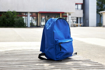 Back to school. A blue backpack, a schoolbag on a bench in the schoolyard. The beginning of the school day, year. The first time in first class
