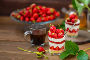 Strawberry dessert in a glass with a decor of cut strawberries standing on a wooden background