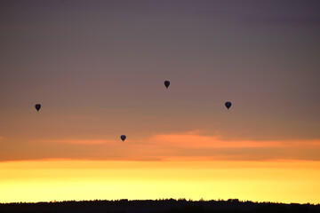 Hot air balloons over woods on the sunset sky background