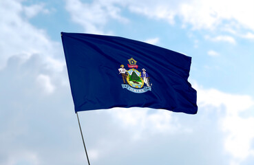Flag of Maine in front of blue sky, realistic 3D rendering