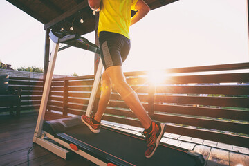 The guy jogging on treadmill on terrace of his home. Social isolation or quarantine concept