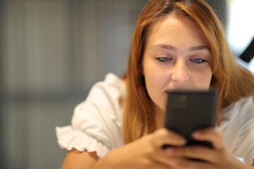 Fototapeta na wymiar Woman checking cell phone at home