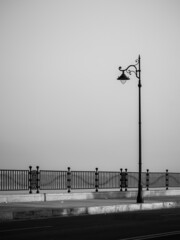 Vertical shot of a street light with a sidewalk and fence