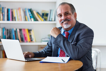 Hispanic senior adult businessman at computer