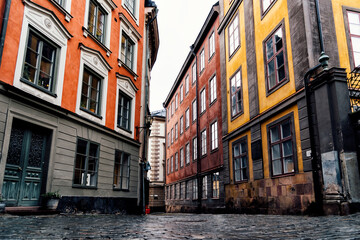 Fototapeta na wymiar Cobblestoned street and colorful houses in Gamla Stan, Stockholm after rain. The Old Town is one of the largest and best preserved medieval city centers in Europe