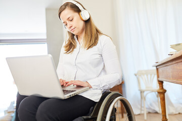 Woman in wheelchair working on laptop computer at home