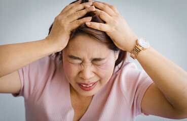 Middle age senior Asian woman feeling pain from sudden headache and brain stroke attack and hold...
