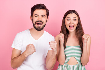 Photo of astonished couple celebrate victory raise fists wear casual outfit isolated pink color background