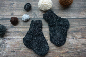 Fototapeta na wymiar Small and warm newborn socks made of woolen yarn, on dark wooden background