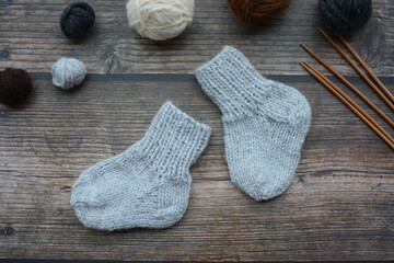 Small and warm newborn socks made of woolen yarn, on dark wooden background