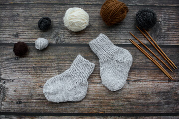 Small and warm newborn socks made of woolen yarn, on dark wooden background