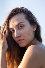 closeup portrait of sexy seductive young thin woman in blue bikini outdoors. face of attractive asian fit female with long hair on sunny day