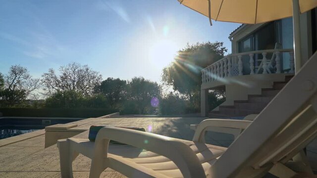 Passage forward overlooking the garden, luxury holiday home with pool and garden. With sun loungers and parasols on the veranda.