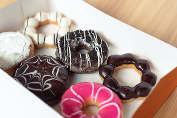 Colorful tasty delicious donuts in orange box on wooden table