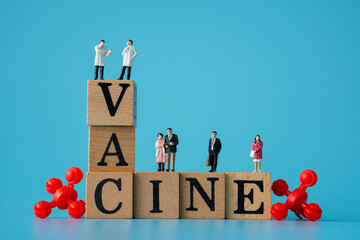 miniature of doctor and people wearing masks. red virus with Wooden cubes with words ''vaccine