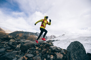 Woman trail runner cross country running up to winter snow mountain top
