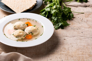 Traditional Jewish matzah ball soup on wooden table. Copy space