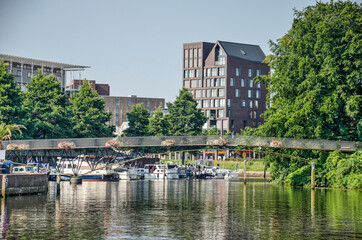 Fototapeta na wymiar Zwolle, The Netherlands, August 4, 2021: view of the canal surrounding the old town with modern housing developments, a marina and a bridge for pedestrians