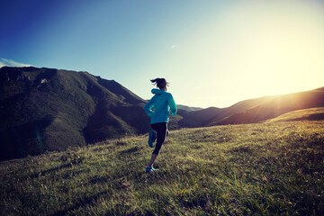 Fototapeta premium Young woman runner running at mountain top