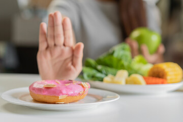 Diet, Dieting asian young woman or girl use hand push out, deny sweet donut and choose green apple, salad vegetables, eat food for good healthy, health when hungry. Close up female weight loss person.