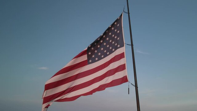 The American flag fluttering in the wind at sunset. A frame shot on the drone. High quality 4k footage