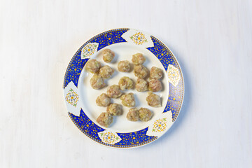 Uncooked pork meatballs on white and blue plate