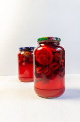 compote made of plums, lemon, mint in glass jar on white background
