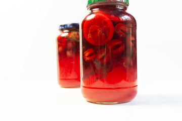 compote made of plums, lemon, mint in glass jar on white background