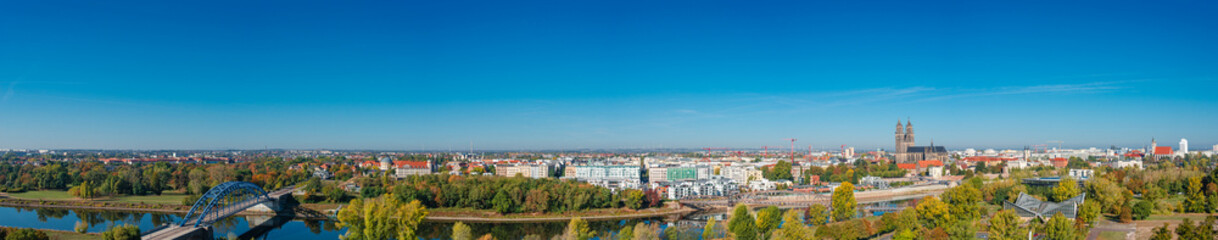 Fototapeta na wymiar Panoramic bird view at Cathedral of Magdeburg, modern luxury houses and bridge during golden Autumn at blue sky and sunny day, Magdeburg, Germany. Concept of historical architecture heritage.