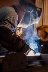 Welder works with a metal profile, iron construction production.