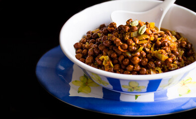 Closeup,front view of Bengal Gram or Kala Chana Masala,Black Chickpea gravy.Famous dish from Punjab,Delhi. Made during Indian festivals like Navratri,Janamashtami.Isolated on black background.