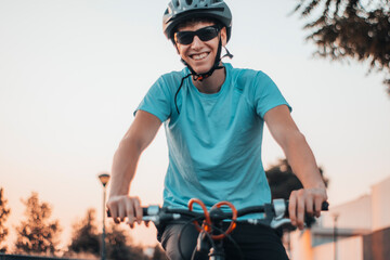 Fototapeta na wymiar Adolescente joven sonriente y feliz con casco y gafas de ciclismo haciendo deporte con la bicicleta 