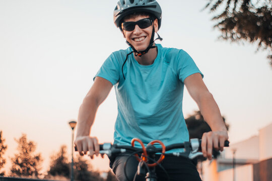 Adolescente joven sonriente y feliz con casco y gafas de ciclismo haciendo deporte con la bicicleta 