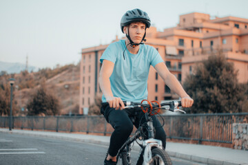 Adolescente de ruta haciendo ciclismo en la carretera de la ciudad junto a la puesta de sol