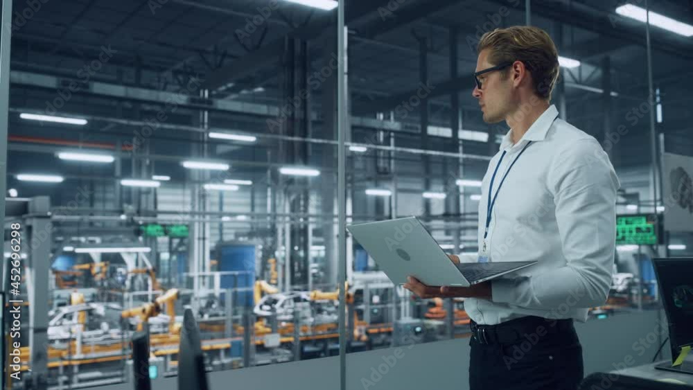 Poster handsome engineer in glasses and white shirt using laptop computer and looking out of the office at 