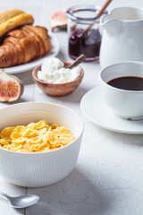 Breakfast table with cornflakes, croissants and cup of coffee. Gray tile background, copy space.