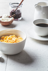 Breakfast table with cornflakes and cup of coffee. Gray tile background, copy space.