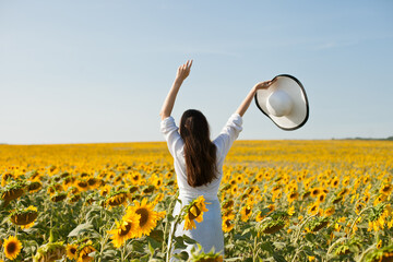 girl in a field of sunflowers throwing hat in the air