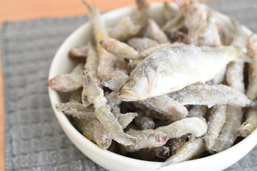 frozen sardines in a white bowl held by a woman's hands