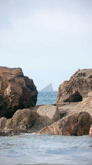 Fototapeta na wymiar Isla en el horzonte entre dos rocas costeras