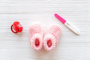 Pregnancy test and pink baby girl booties. Morherhood and pregnancy concept