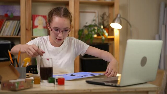 Home school drawing lesson online. Spbas Girl art student draws and shows picture of tree with bare branches to teacher at video call via laptop at home
