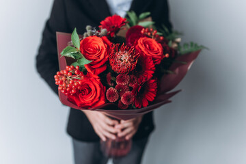 Bouquet of red flowers in hands on isolated background
