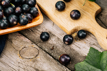 Naklejka na ściany i meble Fresh black currant. A handful of berries on a wooden table