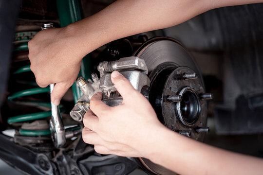Home service concept : A Man using a wrench to remove the locking nut of Brake caliper in service shop maintenance concept brake system
