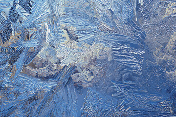 Fantasy ice crystals. Fiery winter wallpaper. Drawing of frost on window glass. A pattern of leaves and stems of magical fantastic plants. Abstract mystical lace background. Macro