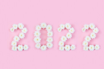 The inscription 2022 from natural white flowers on a pink background. Christmas and New Year concept.