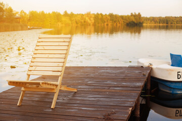 Fototapeta na wymiar Wooden dock with lounge chair on pier on the calm lake in the middle of the forest