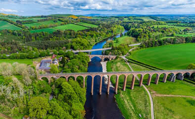 An aerial view of the Leaderfoot Viaduct, medieval bridge and modern road bridge in Scotland on a...