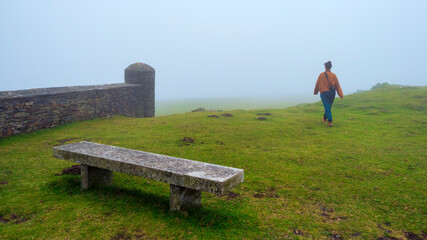 Una chica joven pasea entre la niebla de un monte de Galicia